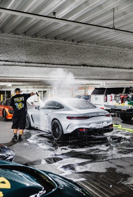 Nico pressure-washing a Mercedes-AMG GT at the rally